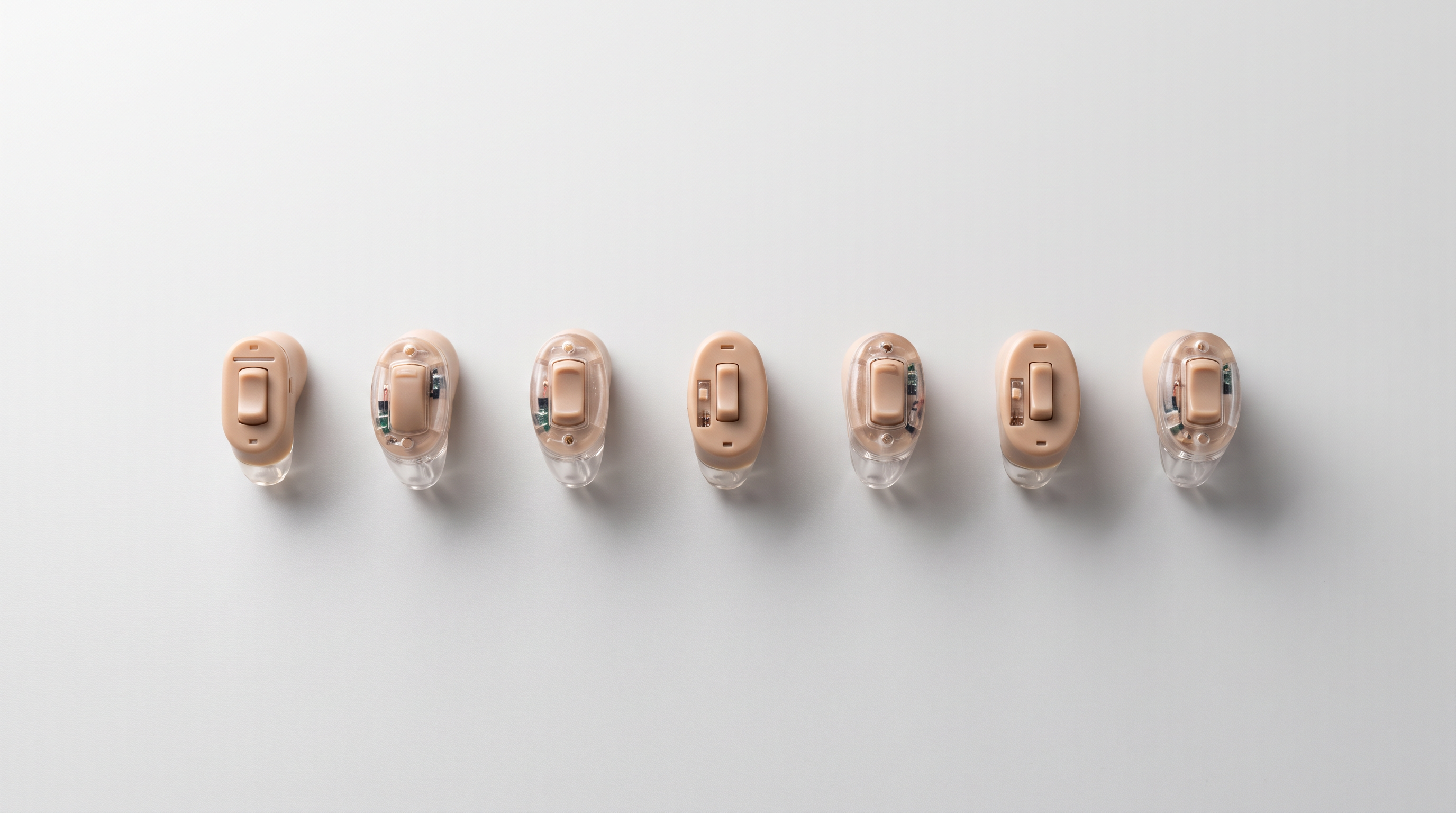 Seven invisible hearing aids laid out side by side for comparison testing